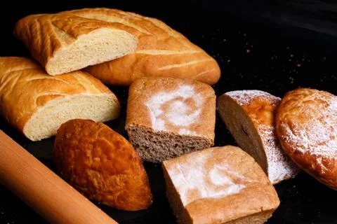 Baking on a black background with a rolling pin. Lots of pastries and bread. 库存照片