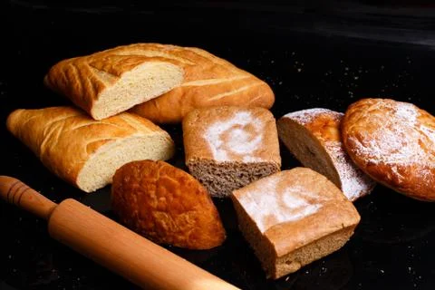 Baking on a black background with a rolling pin. Lots of pastries and bread. Stock Photos