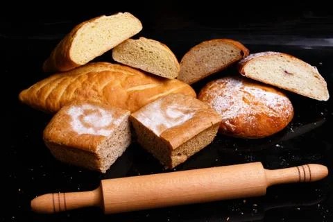 Baking on a black background with a rolling pin. Lots of pastries and bread. Stock Photos