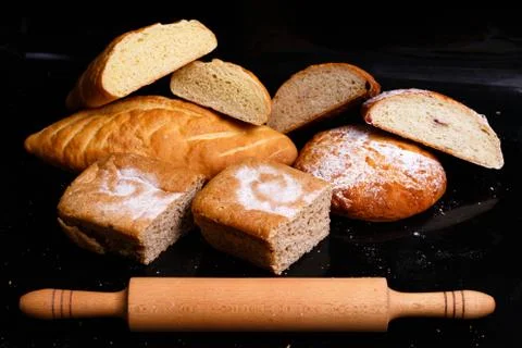 Baking on a black background with a rolling pin. Lots of pastries and bread. Stock Photos