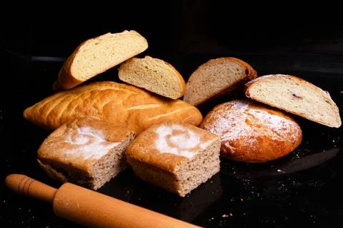 Baking on a black background with a rolling pin. Lots of pastries and bread. Stock Photos