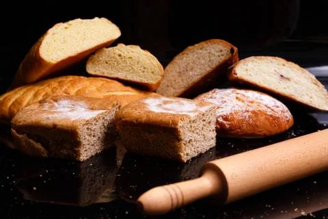 Baking on a black background with a rolling pin. Lots of pastries and bread. Stock Photos