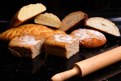 Baking on a black background with a rolling pin. Lots of pastries and bread. Stock Photos