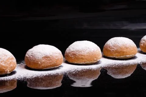 Baking on a black background. White buns sprinkled with powder and flour. Stock Photos