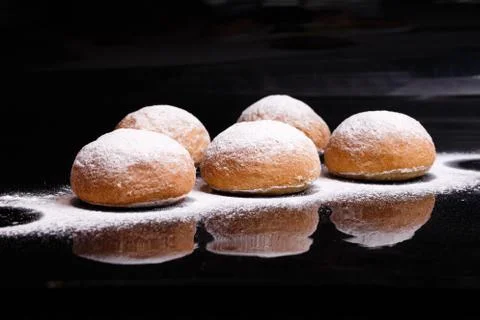 Baking on a black background. White buns sprinkled with powder and flour. Stock Photos
