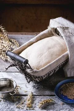 Baking bread. Dough in proofing basket on wooden table with flour, cumin an.. Stock Photos