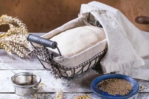 Baking bread. Dough in proofing basket on wooden table with flour, cumin an.. Stock Photos