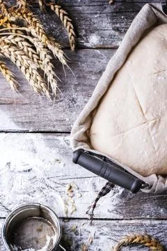 Baking bread. Dough in proofing basket on wooden table with flour and wheat.. Stock Photos