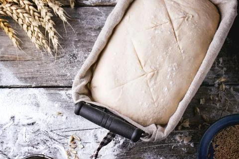 Baking bread. Dough in proofing basket on wooden table with flour, cumin an.. Stock Photos