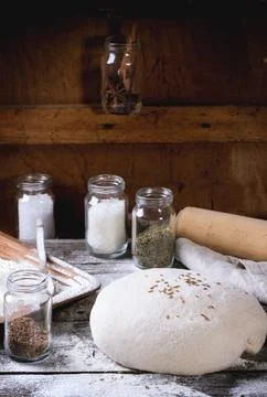 Baking bread. Dough on wooden table with flour, rolling-pin and jars with b.. Stock Photos