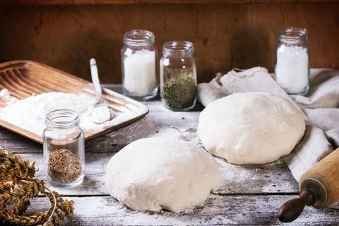 Baking bread. Dough on wooden table with flour, rolling-pin and jars with b.. Stock Photos