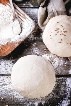 Baking bread. Dough on wooden table with flour, rolling-pin and jars with b.. Stock Photos