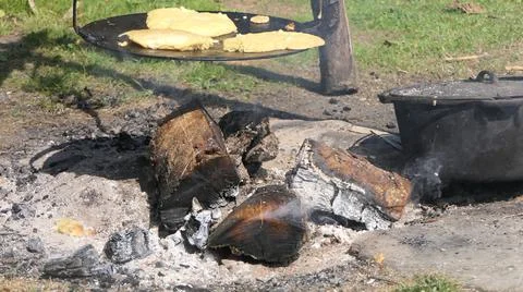 Baking bread on a griddle over a fire outdoors in 1800's America Stock Photos