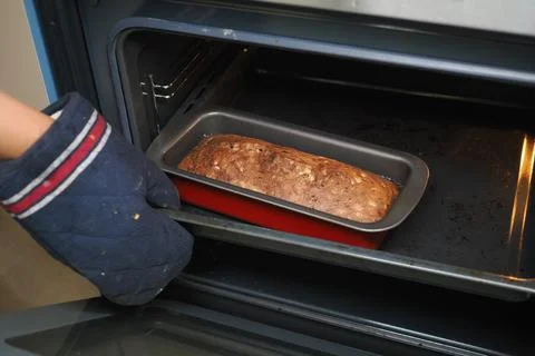 Baking bread in the oven while wearing a cooking glove Stock Photos