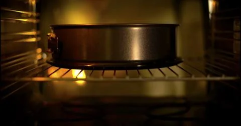 Baking a cake in an oven with warm light shining on the pan near the middle of Stock Photos