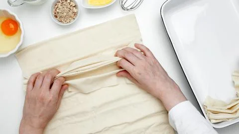 Baking Crinkle Cake. Hands folding phyllo dough with egg, butter, nuts, and m Stock Photos