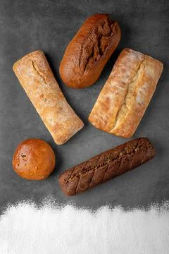 Baking dark background with several baked whole loaves of bread Stock Photos