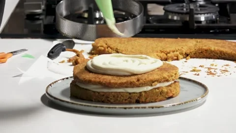 Baking a delicious carrot cake layered with cream cheese frosting in a modern Stock Footage 318392192