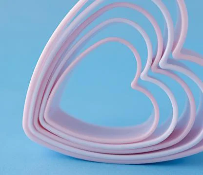 Baking dish in the form of hearts on a blue background, concept photo, symbol Stock Photos