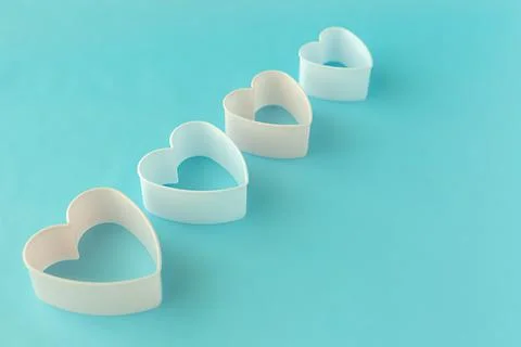 Baking dish in the form of hearts on a blue background, concept photo, symbol Stock Photos