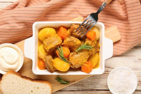 Baking dish of tasty beef stew with sour cream, salt and bread slices on wood Stock Photos