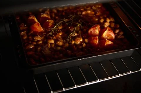 Baking Dish With Tomatoes and Beans in the Oven Under Warm Light Stock Photos