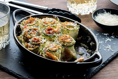 A baking dish of zucchini roll ups with parmesan cheese on top. Stock Photos