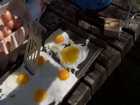 Baking eggs on a camping on a portable stove at camping site, close up Stock Footage 76261601