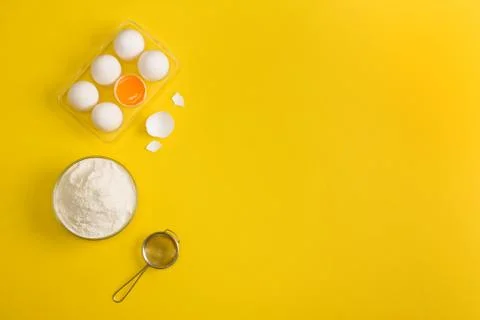 Baking flat lay background with eggs floor sieve on yellow Stock Photos
