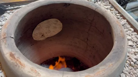 Baking flatbread inside traditional clay tandoor oven, close-up high angle Stock Footage 345166261