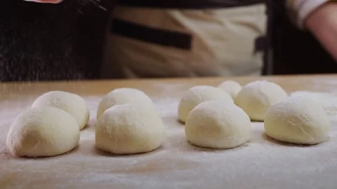 Baking flour falling on small dough balls arranged on wooden surface, cooki.. Stock Footage 334719607