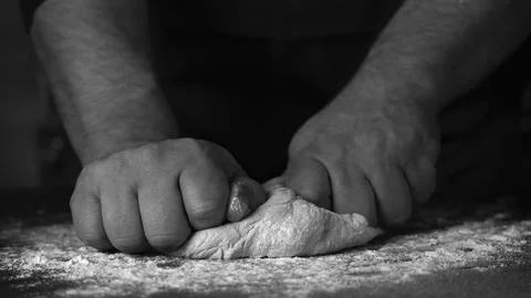 Baking fresh bread in the bakery, hands of male knead dough on kitchen table Stock Photos