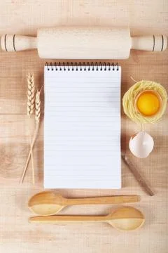 Baking ingredients for cooking and notebook for recipes on a wooden board. Stock Photos
