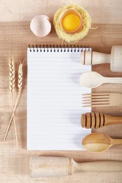 Baking ingredients for cooking and notebook for recipes on a wooden board. Stock Photos