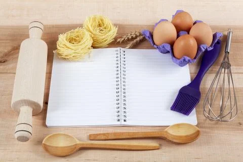 Baking ingredients for cooking and notebook for recipes on a wooden board. Stock Photos