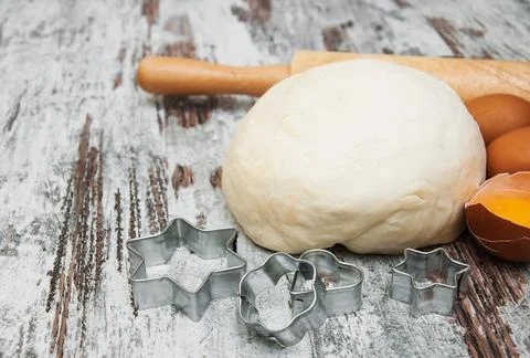 Baking ingredients - eggs, dough, and cutter on a wooden background Stock Photos