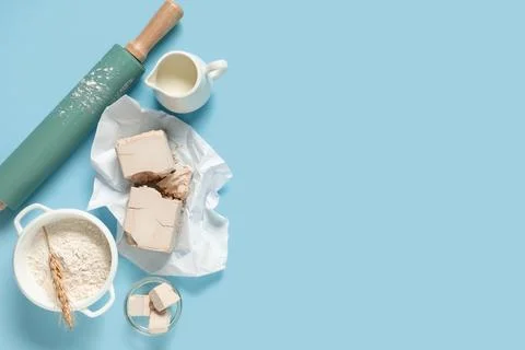 Baking ingredients flat lay with fresh yeast blocks, flour, milk, and rolling Stock Photos