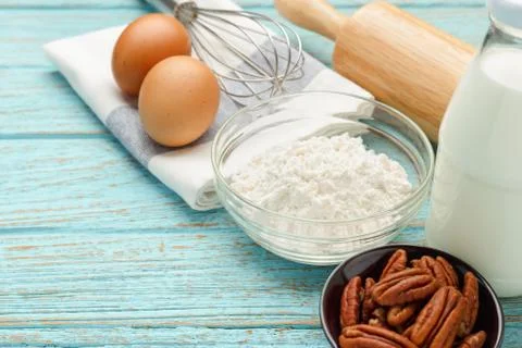 Baking ingredients with flour eggs pecan nuts milk on wood table Фото