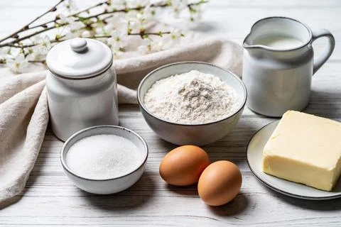 Baking ingredients laid out on a rustic wooden table with delicate white bl.. Foto stock