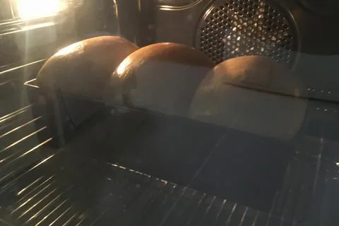 Baking a loaf of bread without the lid placed on rack inside an oven. Stock Photos