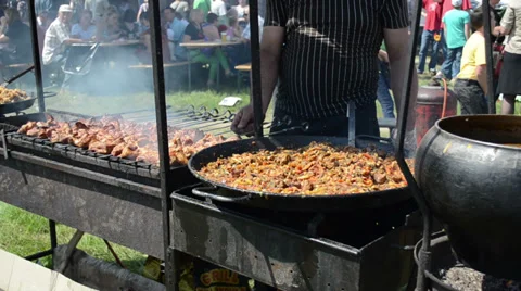 Baking meat and pilaf meal in big dish and hand turn spit Stock Footage 33400264