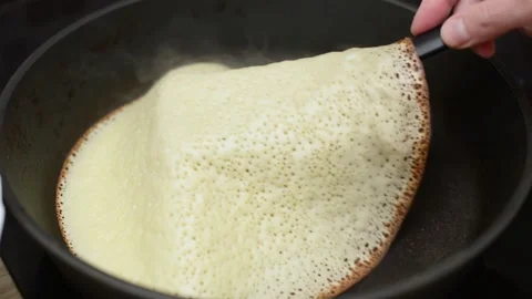 Baking pancakes in a pan, flipping a half-cooked pancake with a spatula Stock Footage 194566109