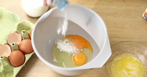 The baking powder is added to the bowl with the eggs. Stock Footage 249084695
