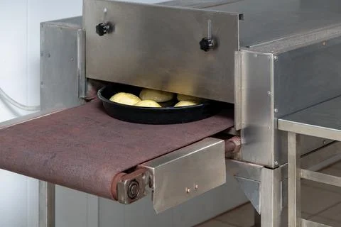 Baking production line. Raw uncooked hamburger buns going to the oven by conv Stock Photos