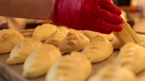 Baking production process in the kitchen. Brushing A Beaten Egg Over Dough On Stock Footage 150820977