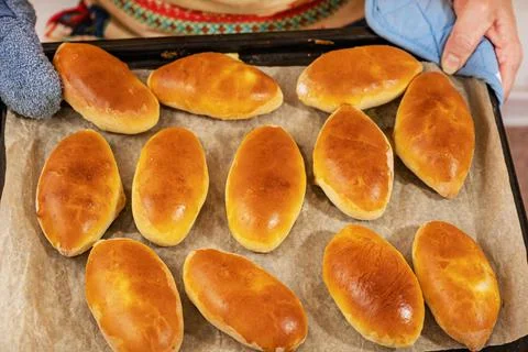 On the baking sheet are ready-made Russian pies with filling. Homemade baking Stock Photos