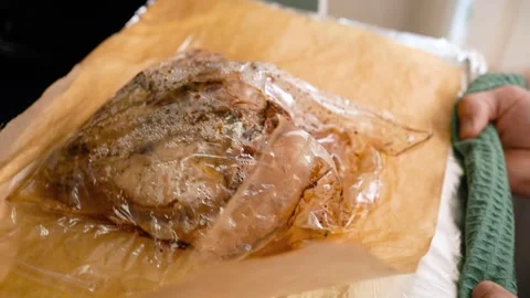 A baking sheet with baked chicken in a bag is removed from the oven. Video stock 250325051
