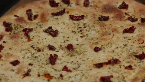 A baking sheet with a baked pizza base. On it are pieces of sun-dried tomat.. Stock Footage 229547198