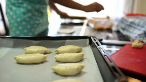 Baking sheet with raw buns against the background of a chef putting stuffing on Video stock 279530816