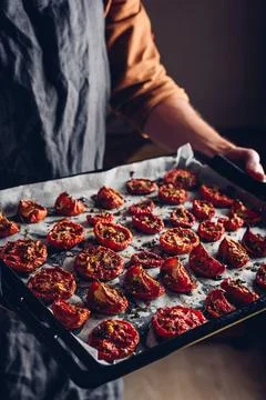 Baking Sheet with Sun Dried Tomatoes with Thyme in a Chefs Hands Stock Photos